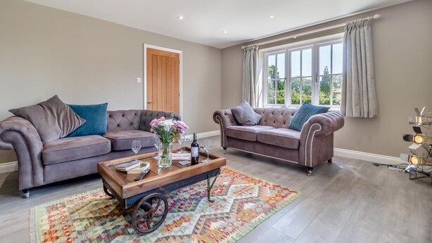 A spacious living room with two sofas, a coffee table, and a large window with curtains. - 2 Bed in Oxborough (oc-r29291) (Oxborough)