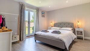 A bedroom with a bed, bedside tables, a wardrobe, and a sliding glass door leading to an outdoor area. - 2 Bed in Oxborough (oc-r29291) (Oxborough)
