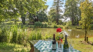Ein Picknicktisch mit karierter Tischdecke, zwei Weinflaschen und einer roten Rose.