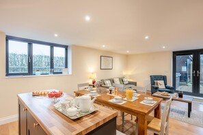 A modern dining area with a wooden table set for breakfast, a sofa, and a chair.