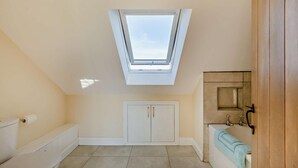 A small, single-room bathroom with a skylight, a toilet, a bathtub, and a wooden cabinet. - 2 Bed in Feering (oc-p29293) (Feering)