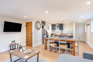 A modern apartment with a dining area, kitchen, and living space.