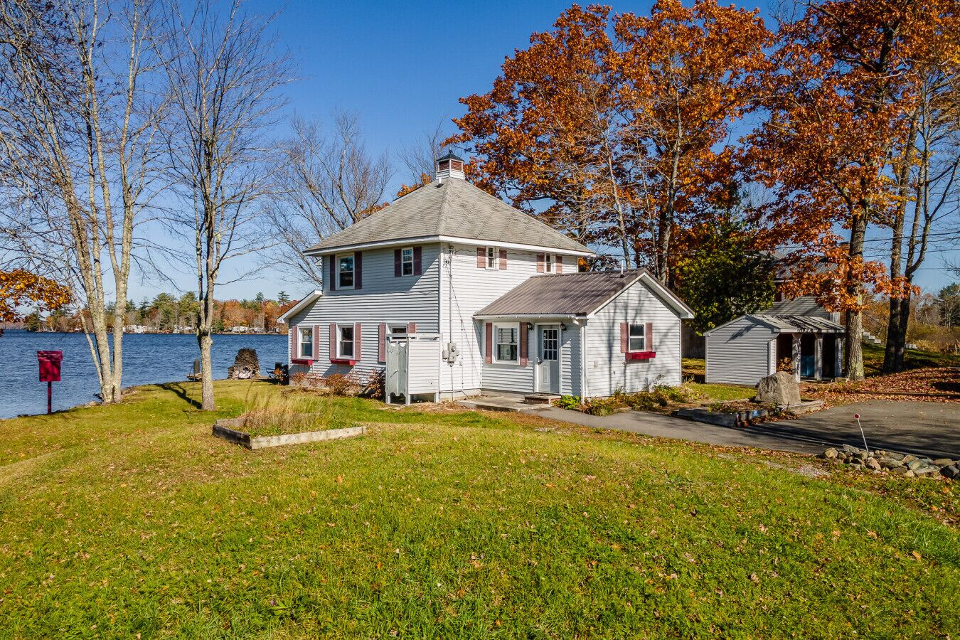 A two-story house with a small attached garage, a dock, and a mailbox.