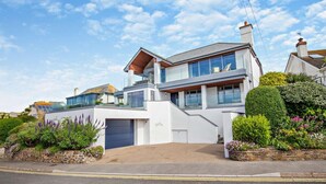 Une maison moderne à deux étages, dotée d’un grand garage, d’un balcon et d’un jardin bien entretenu.