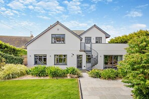 Ein modernes, zweistöckiges Haus mit einer zentralen Treppe, großen Fenstern und einem gepflegten Garten.