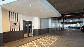 Ett modernt parkeringsgarage med en stilren, minimalistisk design, med ett geometriskt mönster på golvet, en skylt med texten ”LOXWOOD HOUSE” och några parkerade bilar.