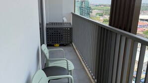 En balkong med utsikt över stadsbilden, utrustad med ett räcke och några stolar.