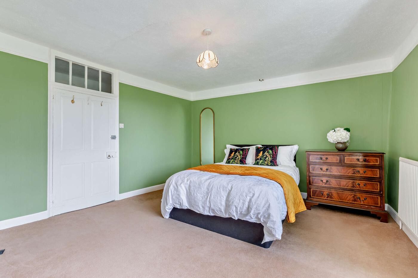 A bedroom with a bed, dresser, and a door.