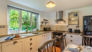 Una cucina con finestra, dotato di piano cottura, lavello e zona pranzo con tavolo e sedie.