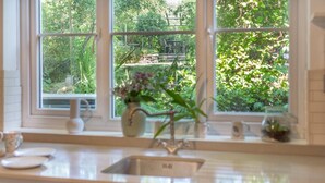 Una cucina con vista su un giardino, un lavello e un vaso con fiori.