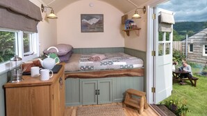 Ein gemütliches Schlafzimmer mit Bett, Nachttisch und Blick ins Freie.