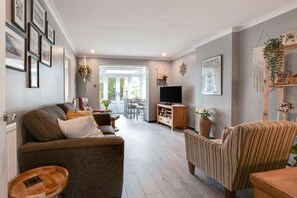 Un salon moderne avec un canapé, un fauteuil et un meuble pour la télévision.