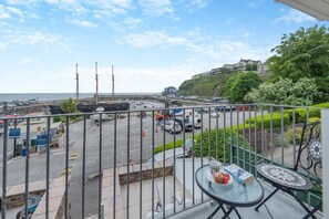 Ein Balkon mit Blick auf einen Yachthafen, ein großes Schiff und einen Hügel mit Gebäuden.
