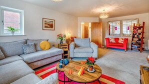 A living room with a grey sofa, a red sofa, a wooden coffee table, and a bookshelf.