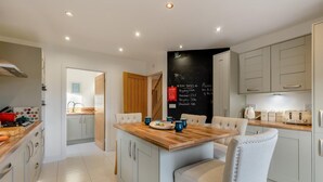 A modern kitchen with a wooden island, grey cabinetry, and a chalkboard with recycling information.