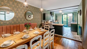 A dining area with a wooden table set for six, a bench, and a view of the kitchen and outdoor area. - 6 Bed in Alnwick (oc-b29336) (Alnwick)