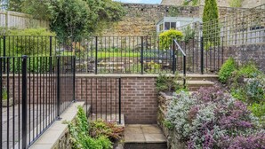 A stone wall with a garden, a wooden fence, and a brick staircase. - 6 Bed in Alnwick (oc-b29336) (Alnwick)