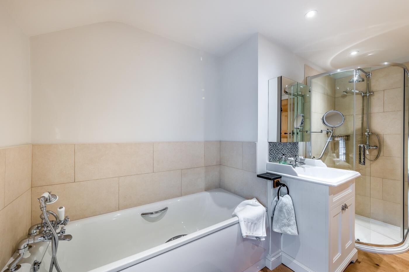 A modern bathroom with a bathtub, a shower, and a vanity with a mirror.
