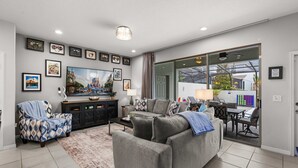 Un salon comprenant un canapé, un fauteuil et une table basse, un téléviseur, ainsi qu’un coin repas avec une table et des chaises.
