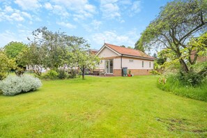A house with a red-tiled roof, a front door, and a small garden with grass and trees. - 1 Bed in North Walsham (oc-f29380) (North Walsham)
