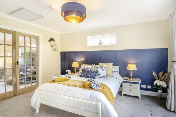 A bedroom with a bed, bedside tables, a window, and a door. - 1 Bed in North Walsham (oc-f29380) (North Walsham)