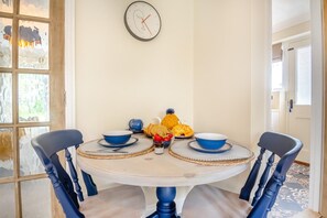 A dining table with two chairs, a clock on the wall, and a window with frosted glass. - 1 Bed in North Walsham (oc-f29380) (North Walsham)