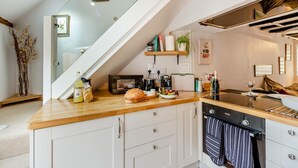A modern kitchen with a wooden countertop, white cabinets, a built-in oven, and a glass staircase. - 1 Bed in Chilham (oc-t29281) (Chilham)