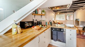 A modern kitchen with a wooden countertop, a built-in oven, and a dining area with a table and chairs. - 1 Bed in Chilham (oc-t29281) (Chilham)