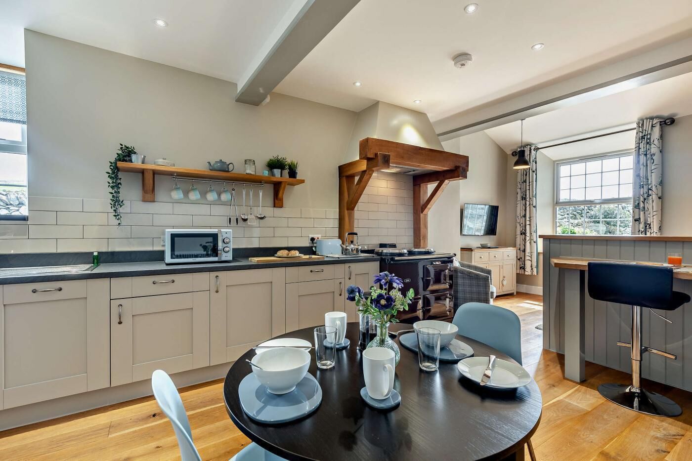 A modern kitchen with a central island, built-in appliances, and a dining area with a round table and chairs.