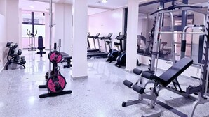 Un gimnasio con diversos equipos de ejercicio, incluyendo cintas de correr, máquinas de pesas y mancuernas.