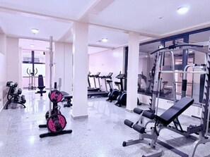 A gym with various exercise equipment including treadmills, weight machines, and dumbbells. - One-Bedroom Apartment #8 (Kigali)