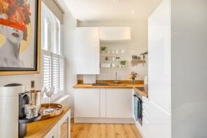 A compact kitchen with white cabinets, a wooden countertop, and a window with blinds. - 1 Bed in Buxton (oc-a29363) (Buxton)