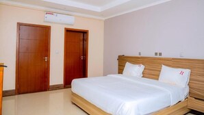 A hotel room with a wooden bed, two doors, and an air conditioning unit on the wall. - One-Bedroom Apartment #9 (Kigali)