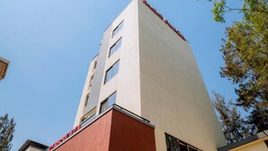 A tall building with a red and beige facade, multiple windows, and a clear sky in the background. - One-Bedroom Apartment #9 (Kigali)