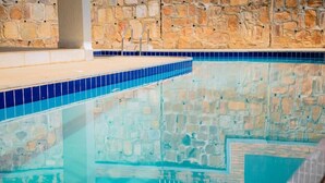A swimming pool with stone walls and blue-tiled edges. - One-Bedroom Apartment #9 (Kigali)