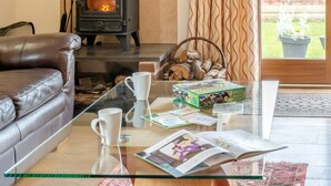 Una sala de estar acogedora con una mesa de centro de vidrio, sofá de cuero y un hogar a leña.