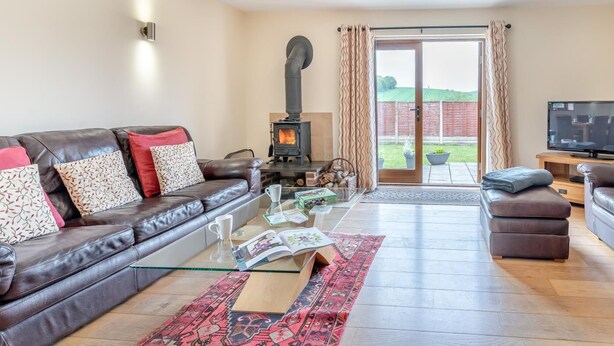 Una sala de estar con sofá de cuero, una mesa de centro de vidrio, chimenea y televisor.