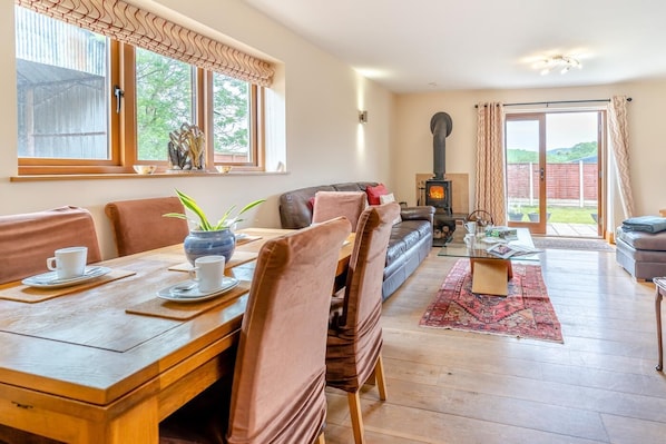 A cozy living room with a fireplace, a dining area with a wooden table and chairs, and a sofa.
