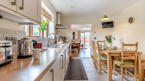 Una cocina moderna con una isla central, un comedor con muebles de madera y un patio exterior visible.