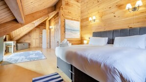 Une chambre dans une cabane en bois, avec un grand lit, une table de chevet et une vue sur l’extérieur.