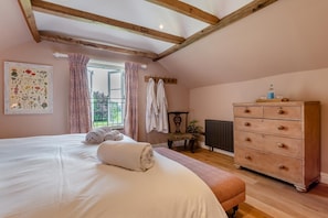 Un dormitorio con una cama grande, cómoda de madera y una ventana con cortinas.