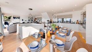 A modern kitchen with a dining area, featuring a central island, contemporary appliances, and a view of the city. - 5 Bed in Aberdovey (oc-t29402) (Aberdovey)