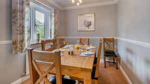 Een eetkamer met een houten tafel gedekt voor vier personen, omringd door houten stoelen.