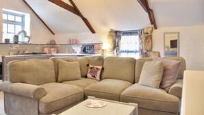 A cozy living room with a sectional sofa, a small table, and a kitchen in the background. - 2 Bed in Trewoon (oc-t29504) (Saint Mewan)