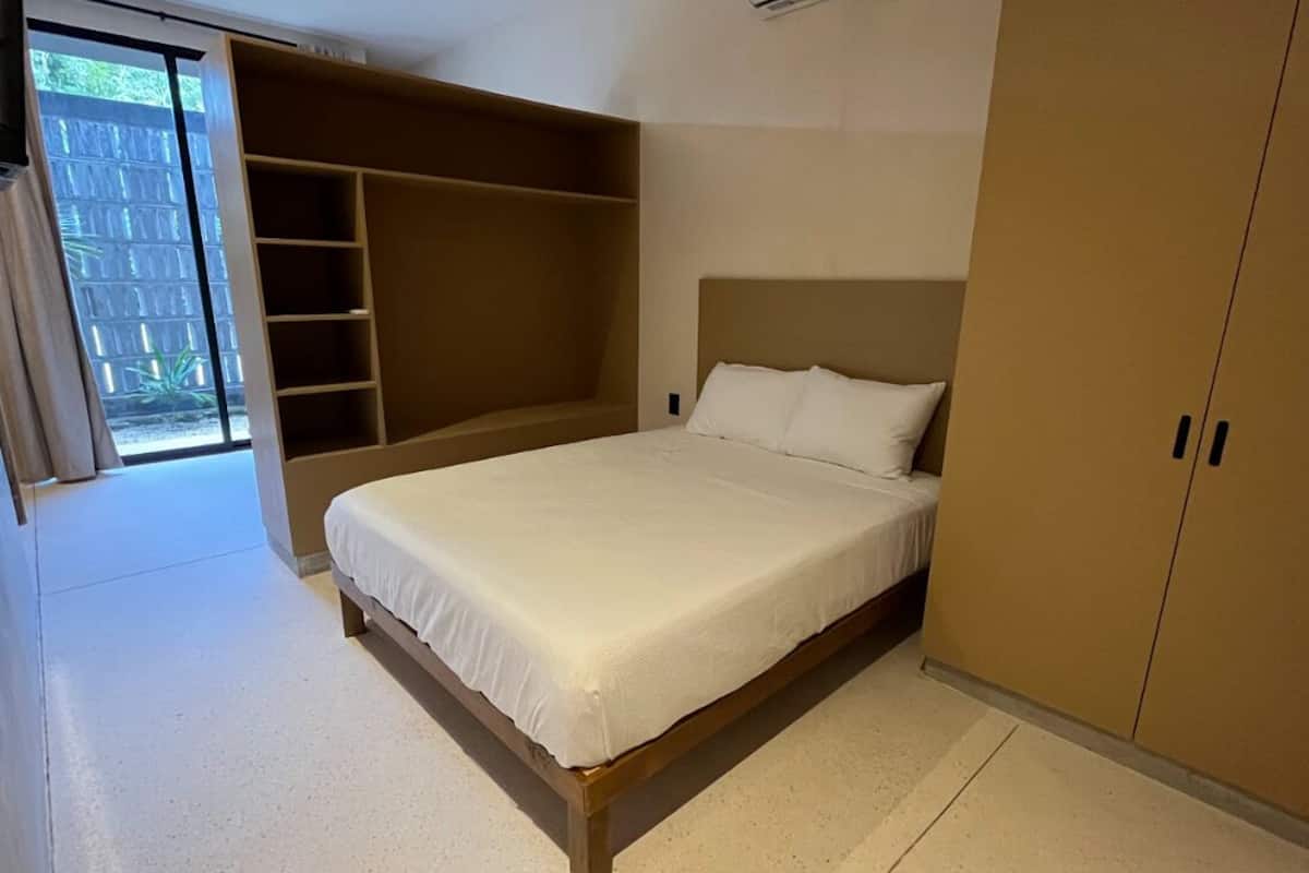 Quarto com cama, guarda-roupa e estantes embutidas.