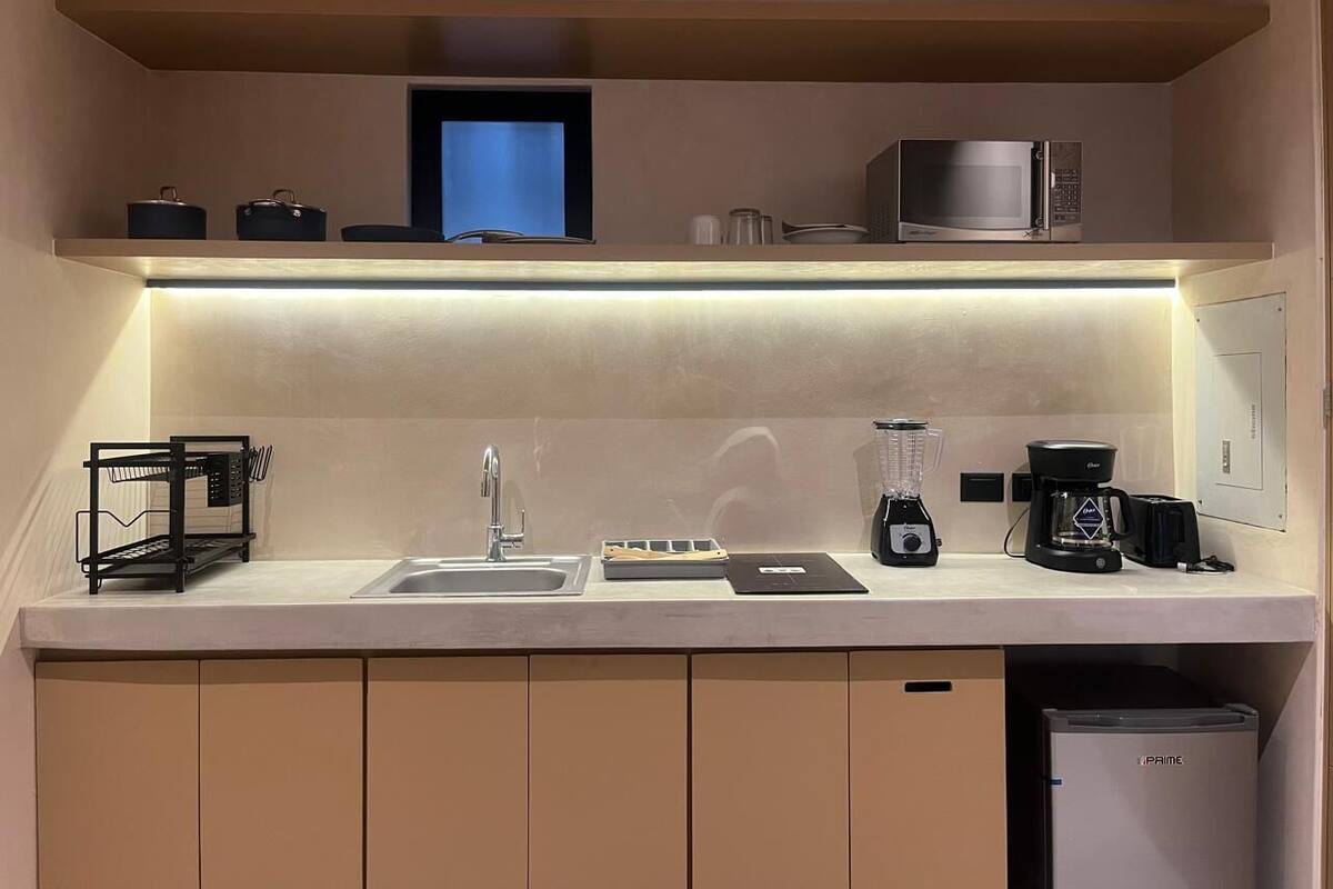 Uma cozinha moderna com micro-ondas embutido, cafeteira e uma pequena geladeira.