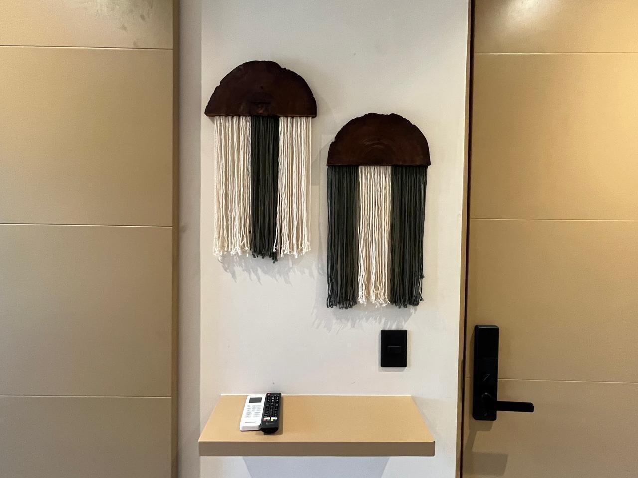 Eine Wand mit zwei Dekorationselementen und einem kleinen Tisch mit einer Fernbedienung.