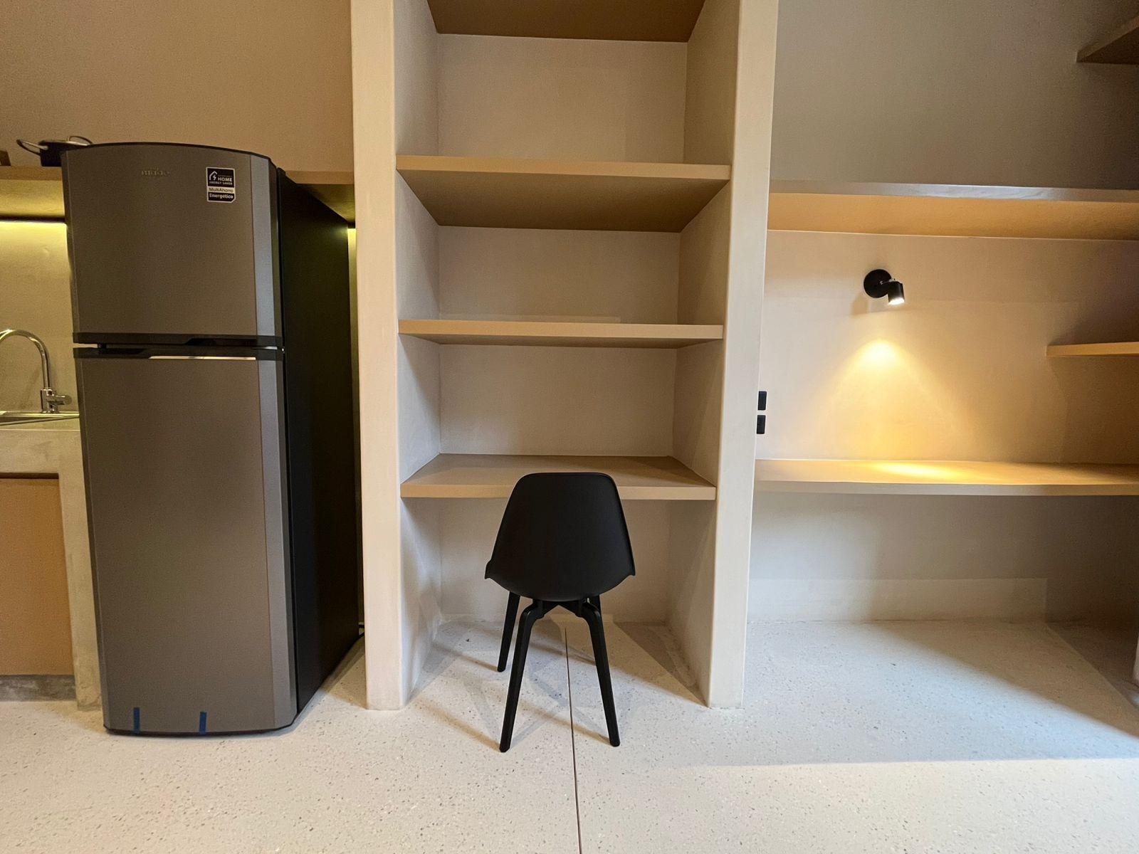 A kitchen with a built-in refrigerator, a sink, and a chair.