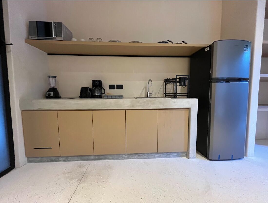 A compact kitchen with a built-in microwave, a coffee maker, and a refrigerator.