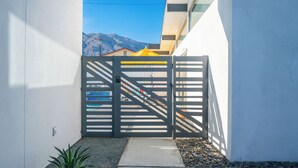 Una entrada cerrada con diseño moderno, un camino de concreto y un pequeño jardín con piedras y una planta.